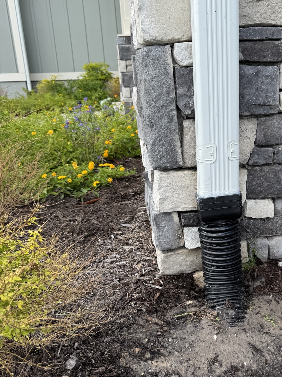 Gutter downspout connected into a buried drain line at the base of a Northeast Florida home
