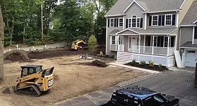 Skid-steer re-grading a yard to create swales