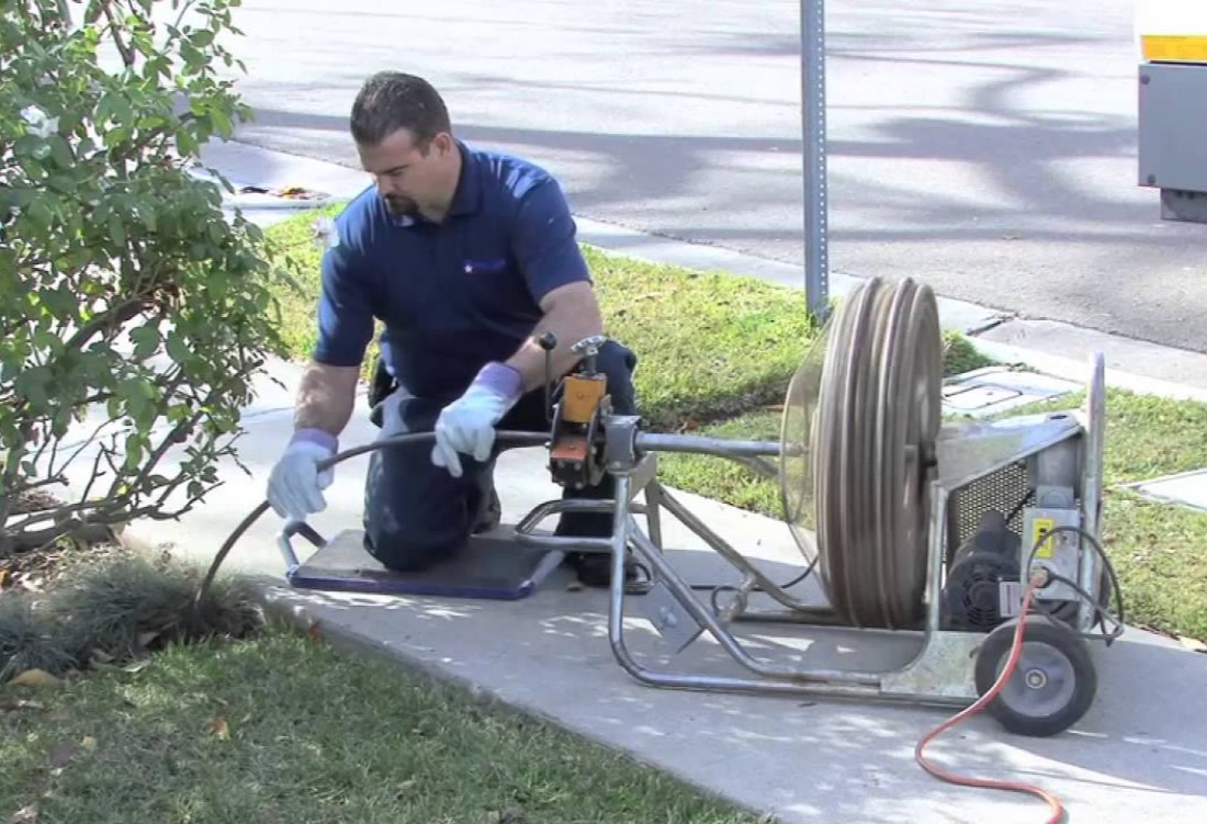 Technician clearing a clogged drain line with a jetter