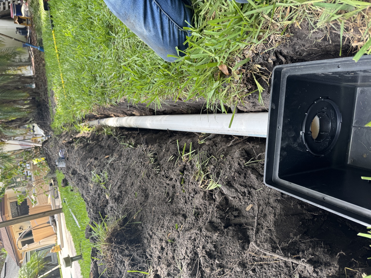 Aqua Premier yard drainage installation — white PVC drain pipe and catch-basin box set in a trench to carry water away from a Nocatee home in St. Johns County